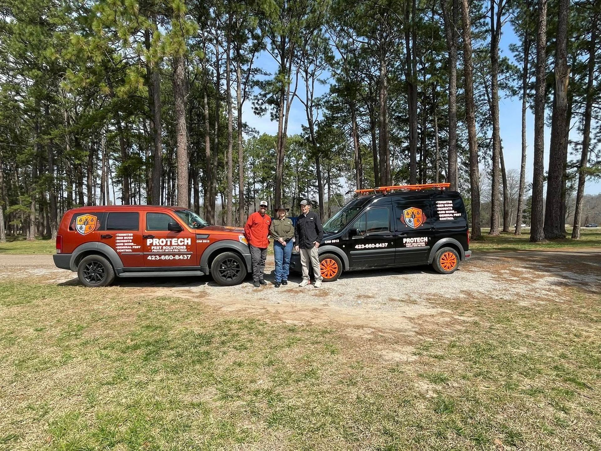 Two men are standing next to two trucks in a field.