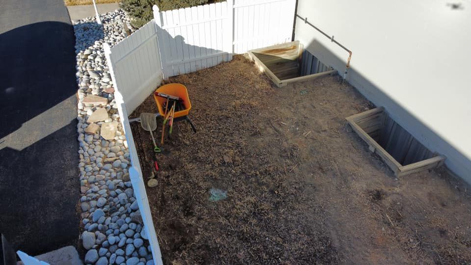 An aerial view of a backyard with a white fence and a wheelbarrow.
