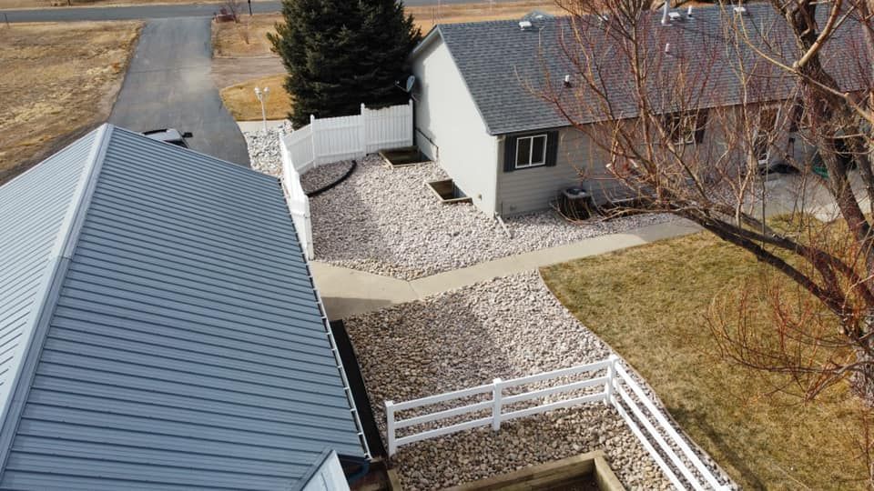 An aerial view of a house with a gray roof and a white fence.