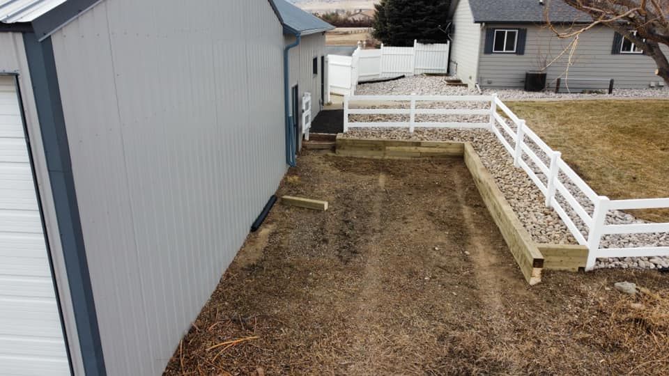 An aerial view of a shed with a white fence in front of it.