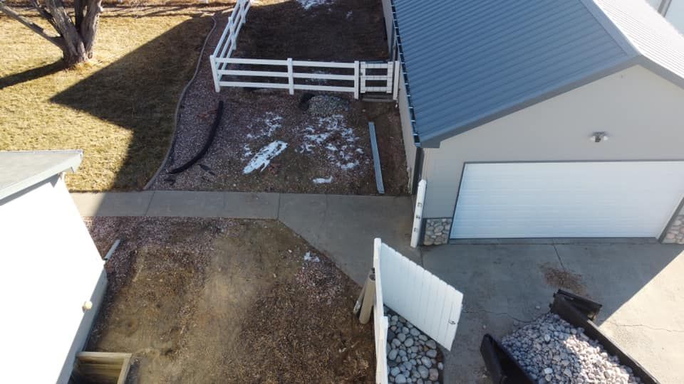 An aerial view of a house with a garage and a white fence