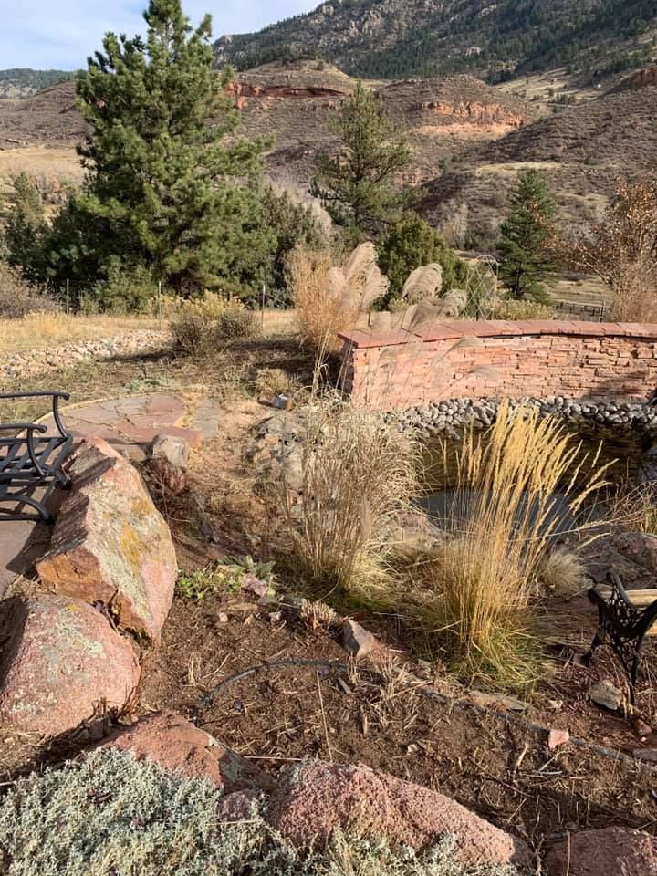 There is a pond in the middle of a rocky area with trees in the background.