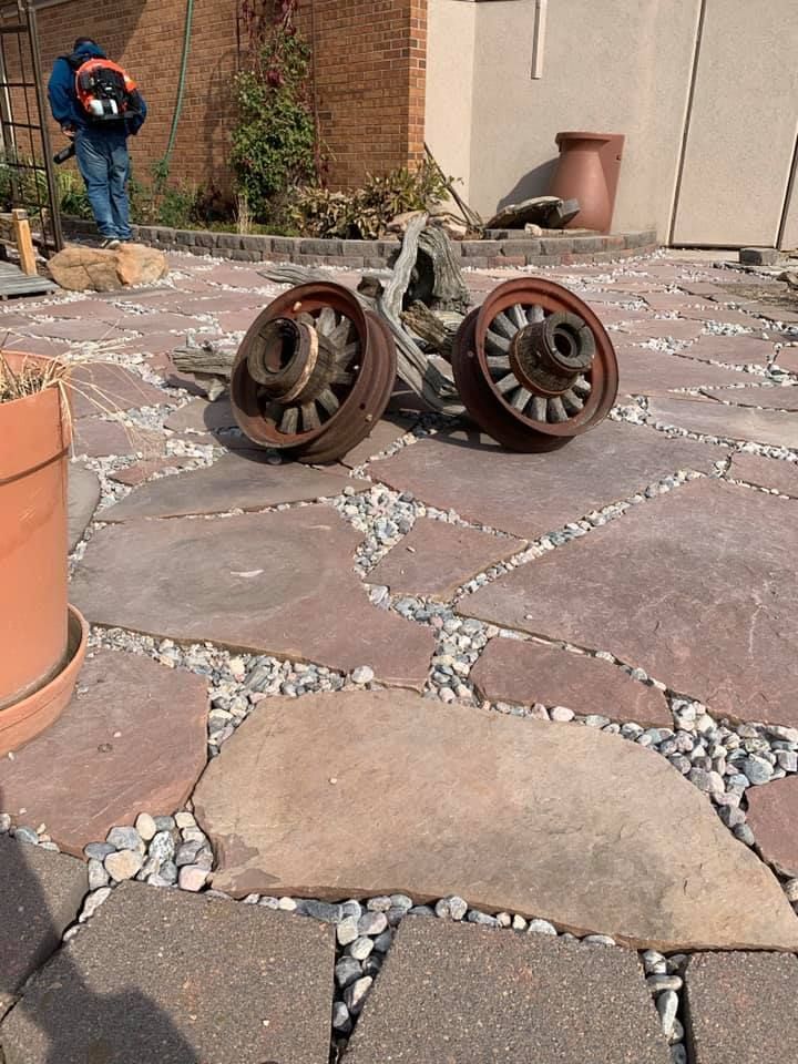 Two rusty wheels are sitting on a stone patio.