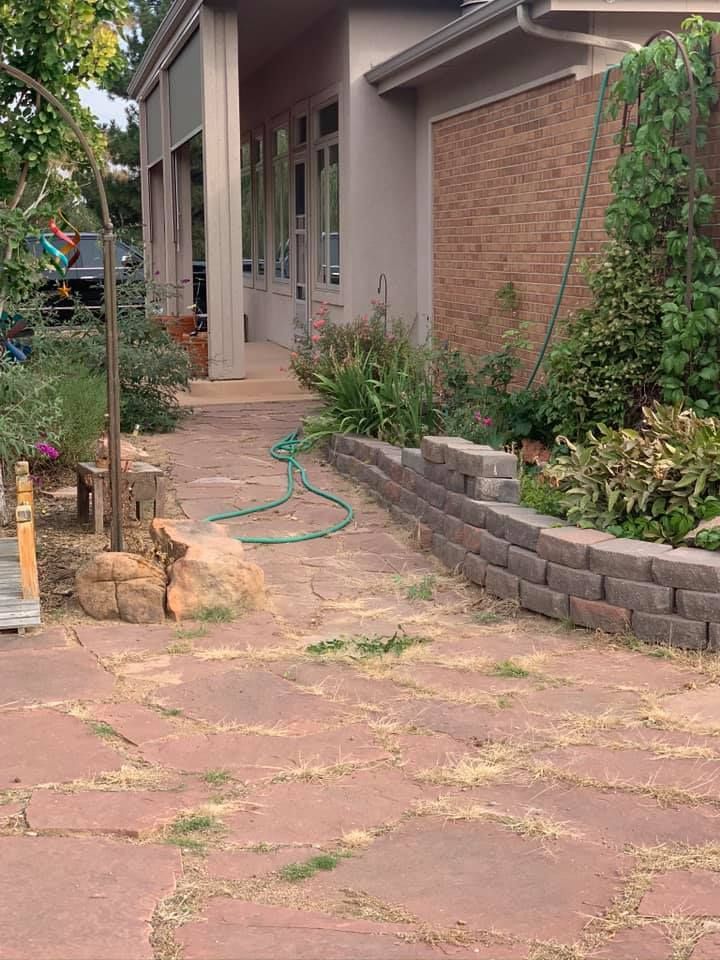 A brick walkway leading to a house with a hose attached to it.