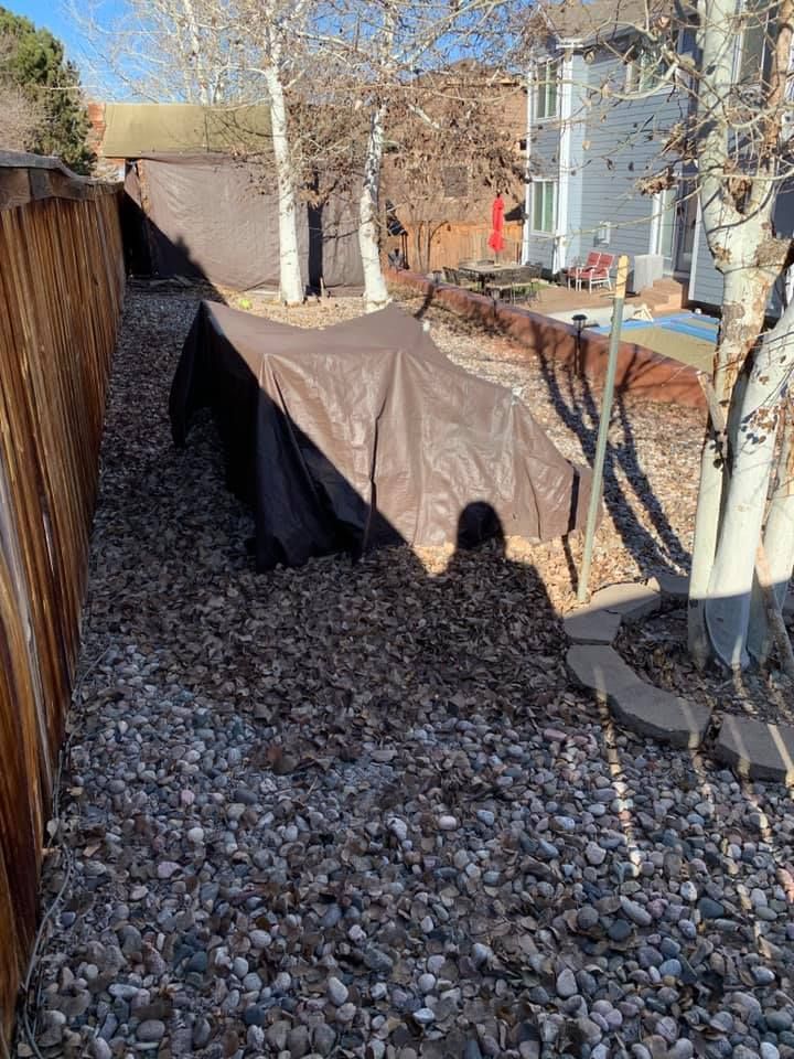A tent is sitting on top of a pile of rocks next to a wooden fence.