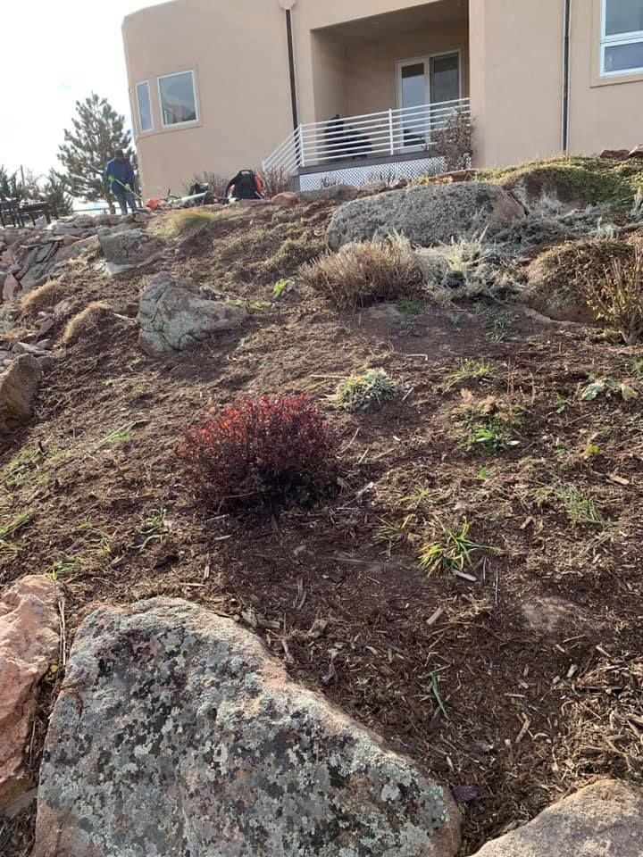 A house is sitting on top of a hill with rocks in front of it.