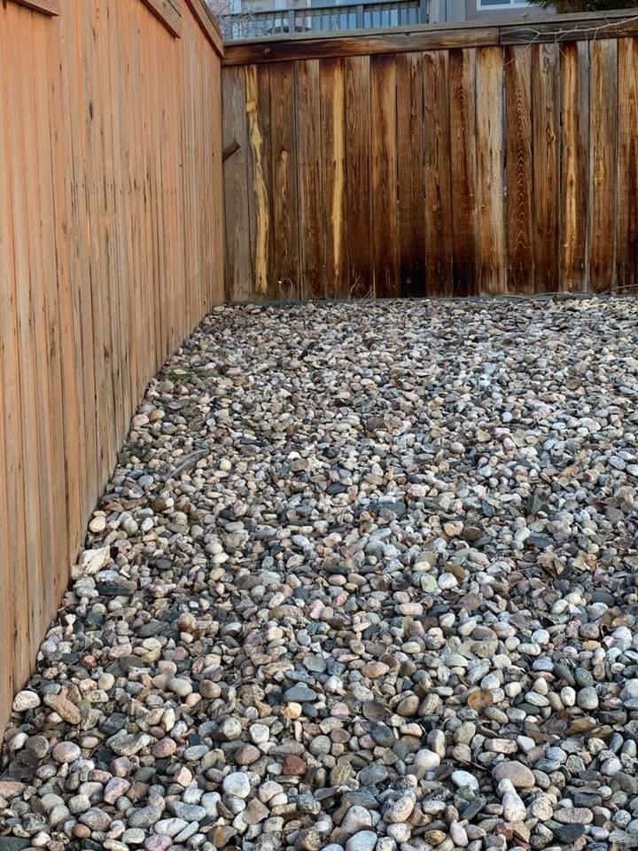 A pile of gravel next to a wooden fence.