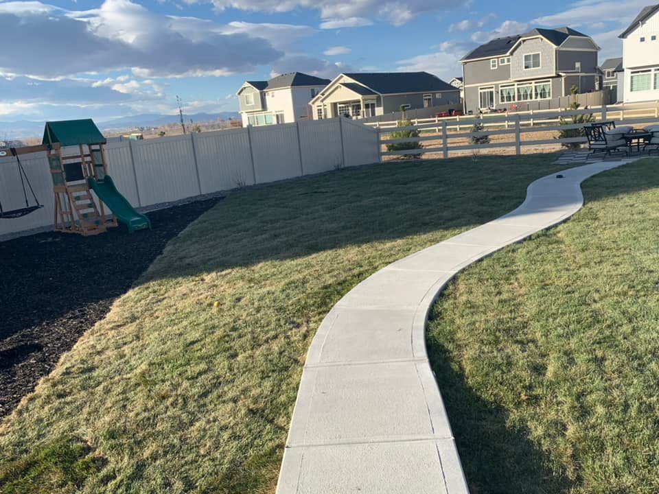 A concrete walkway leading to a playground in a backyard