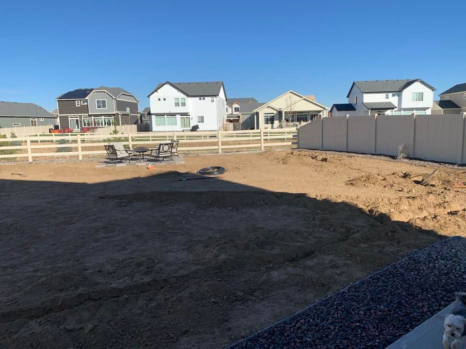 A backyard with a fence and houses in the background