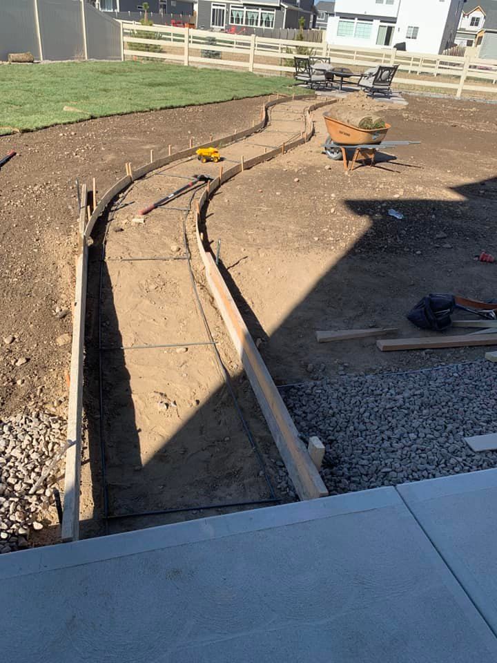 A concrete walkway is being built in a backyard.