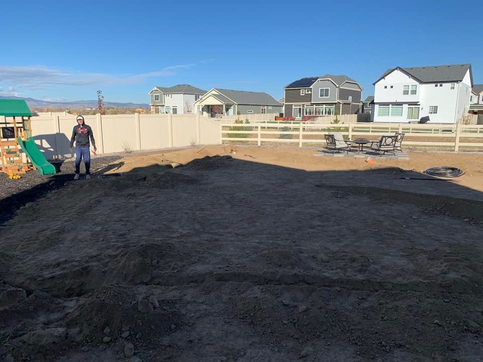 A man is standing in a pile of dirt in a backyard.