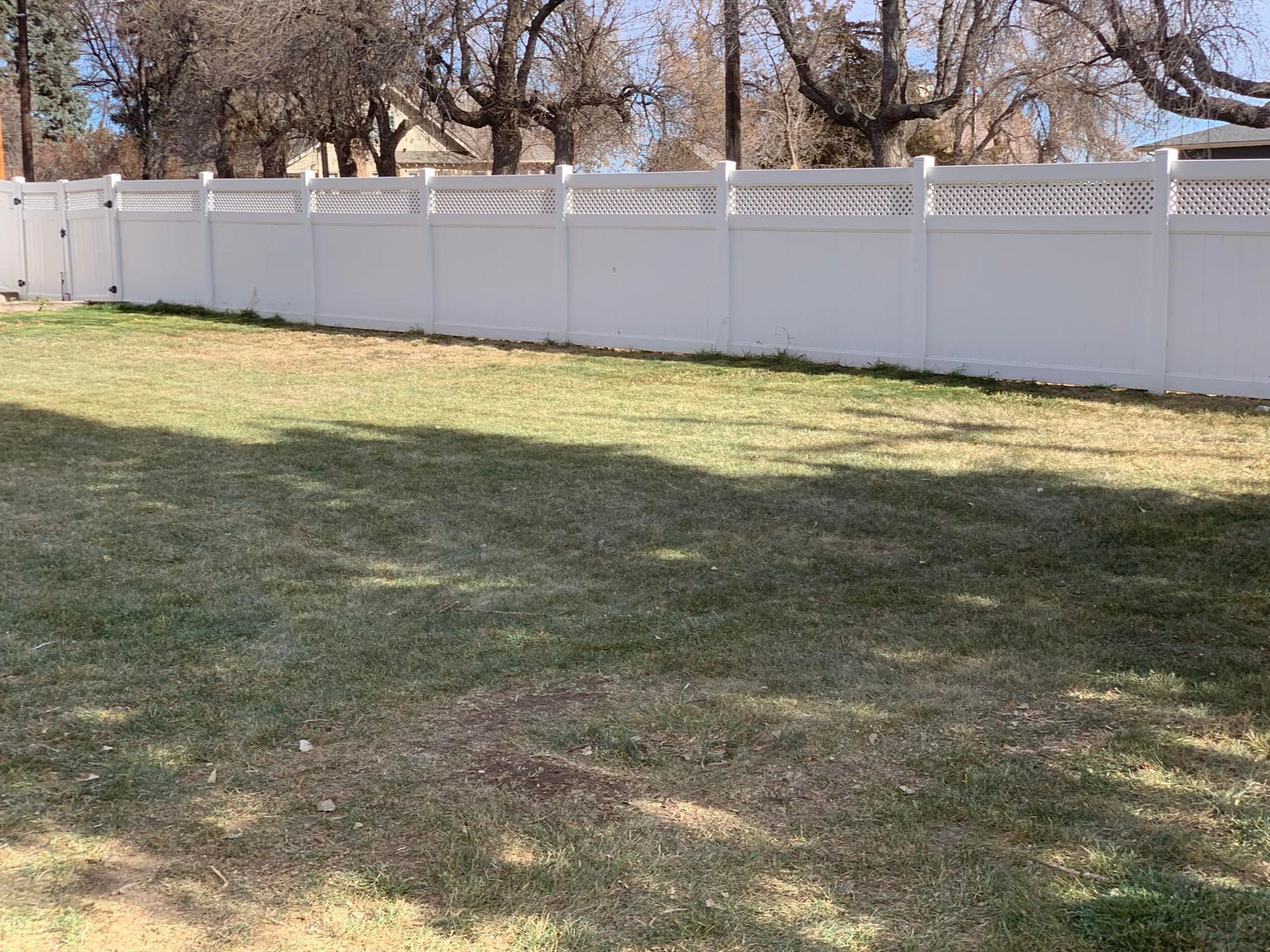 A white fence surrounds a lush green yard.