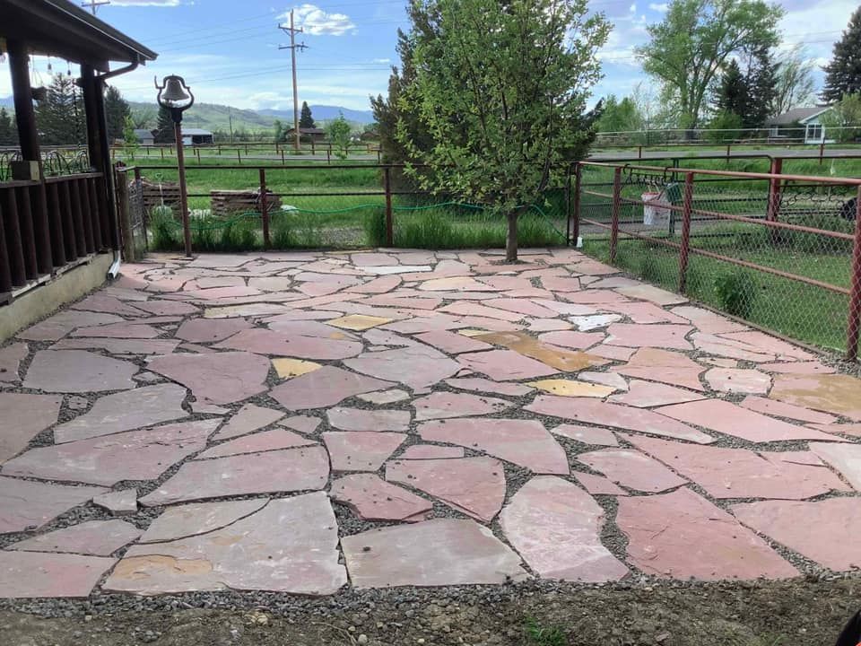 A large stone patio with a fence in the background