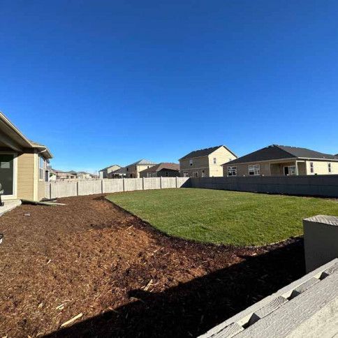 A backyard of a house with a fence and a lot of grass.