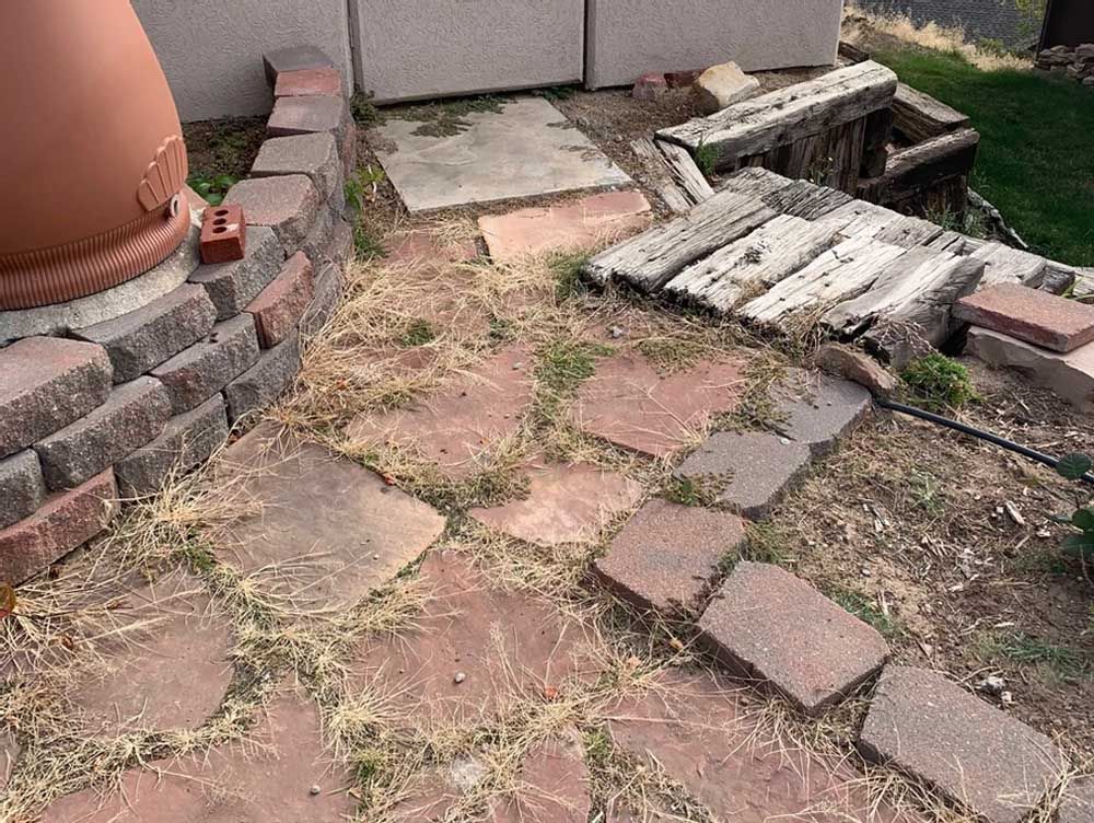 A brick walkway with a few bricks laying on the ground.