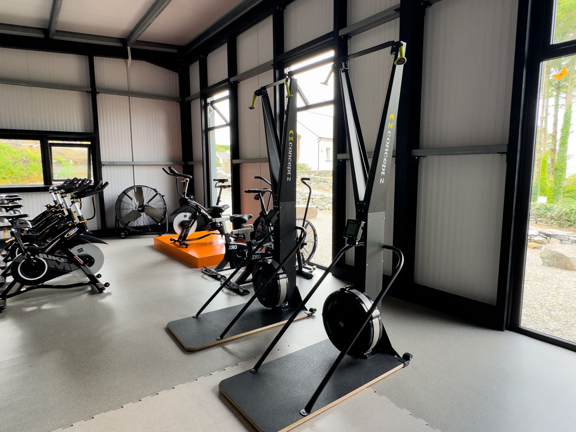 Gym interior with exercise equipment, including ski machines and stationary bikes.