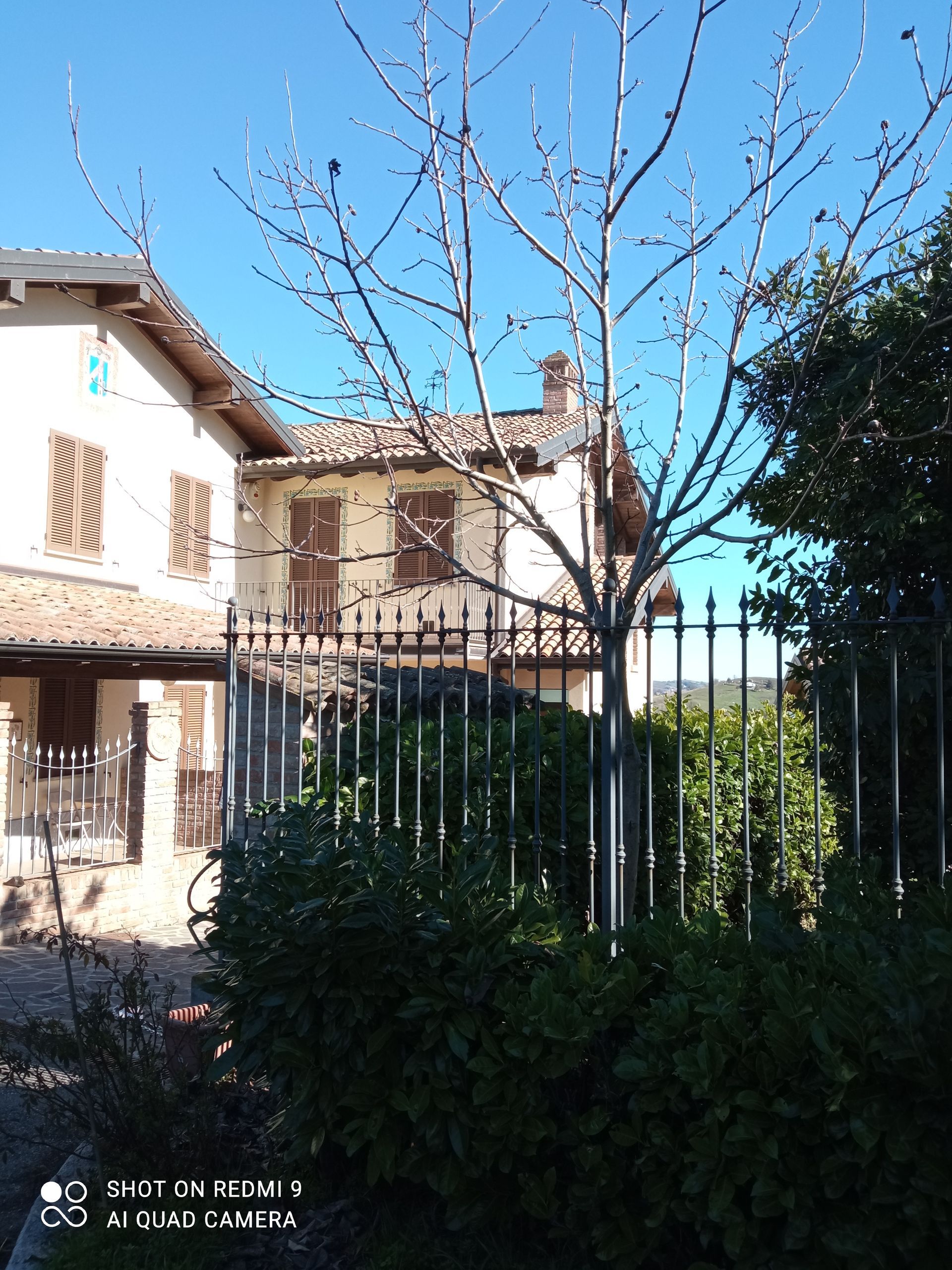 Una casa con una recinzione e un albero di fronte