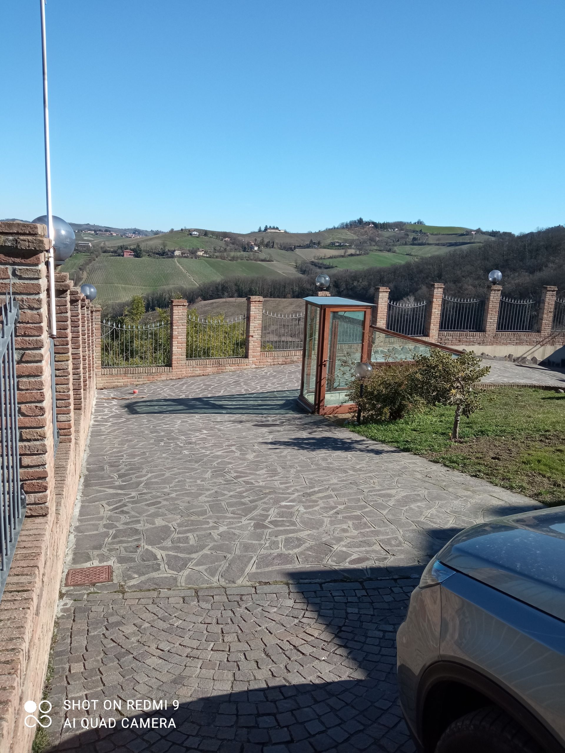 Un'auto è parcheggiata su un vialetto acciottolato accanto a un muro di mattoni.