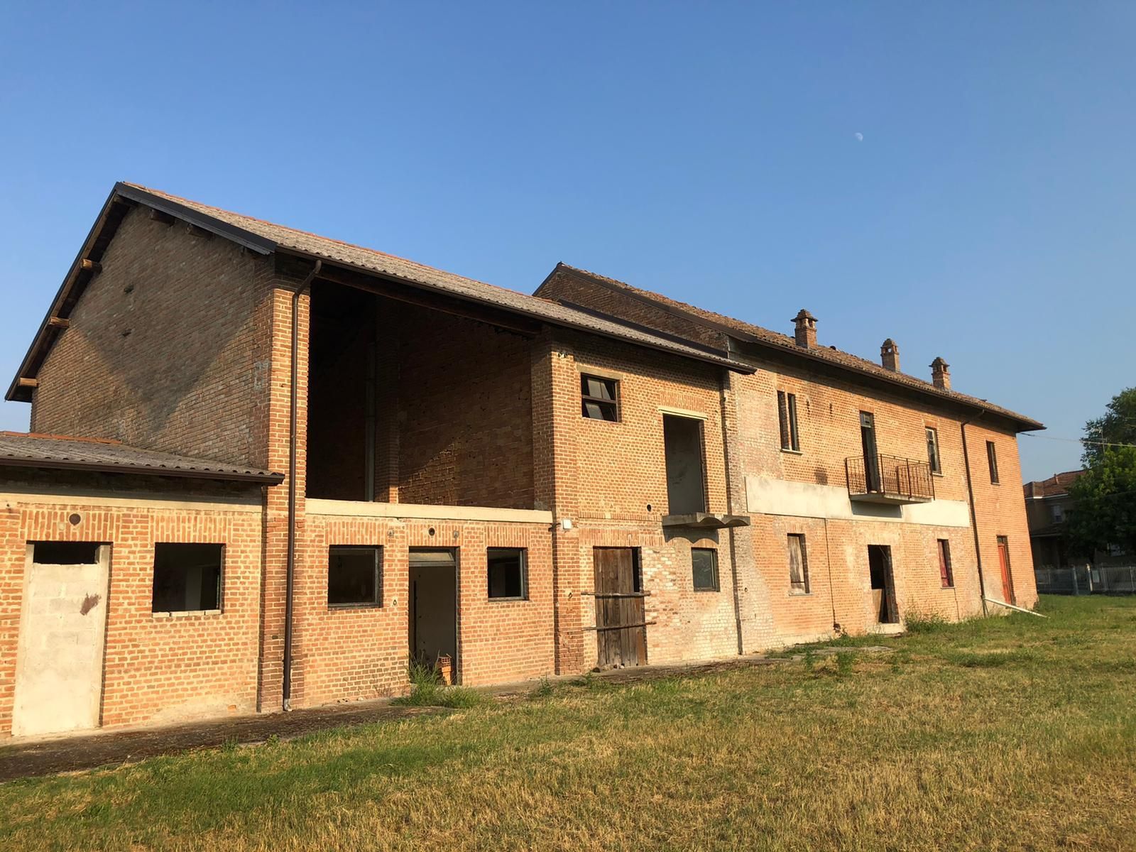 Un grande edificio in mattoni si trova in mezzo a un campo erboso.