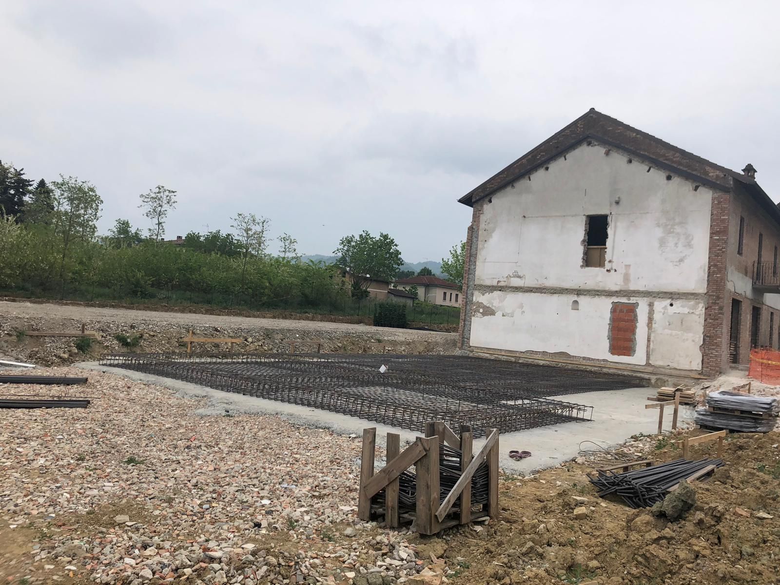 Un grande edificio bianco si trova in mezzo a un campo sterrato.