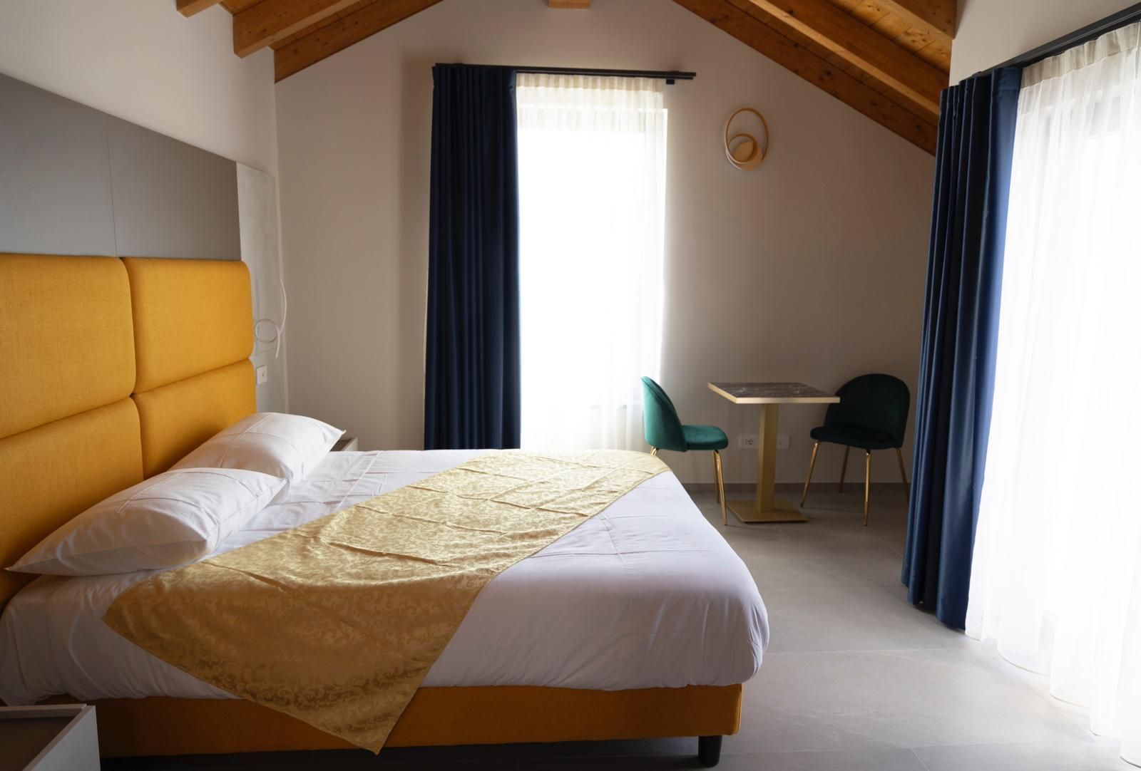 Una camera d'albergo con un letto king size, tavolo e sedie.