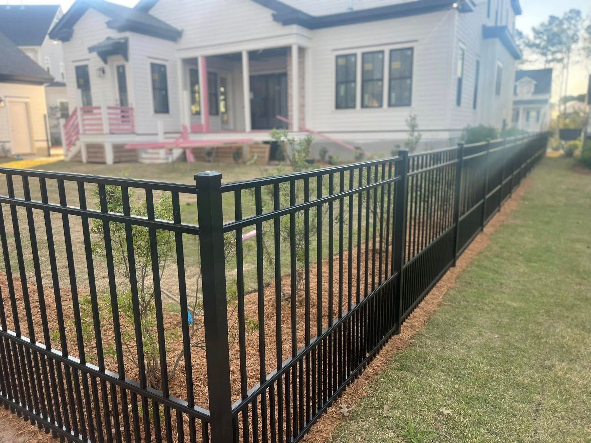 There is a black fence in front of a white house.