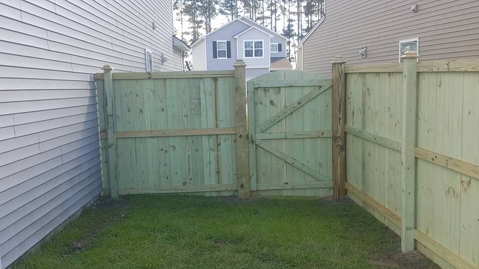 A wooden fence with a gate in the backyard of a house.