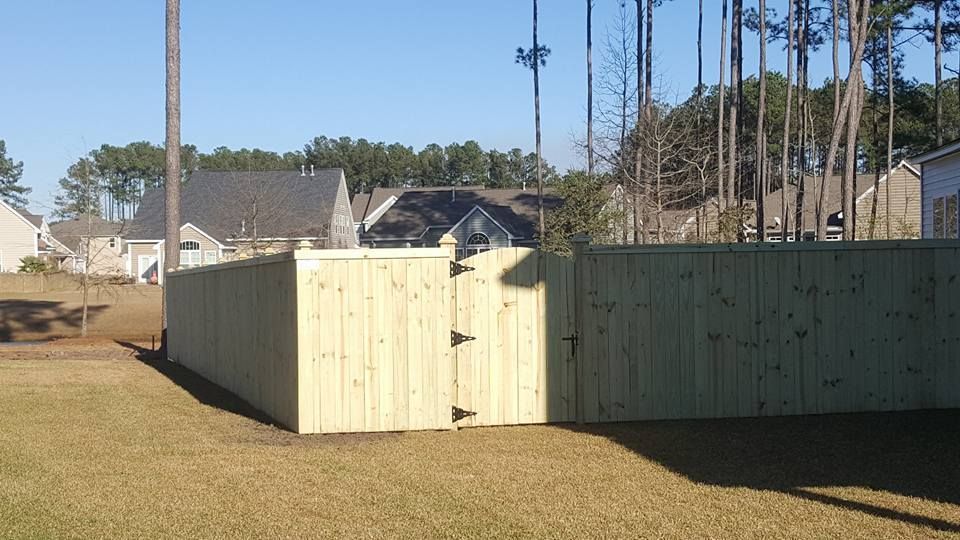 A wooden fence with a gate in the backyard of a house