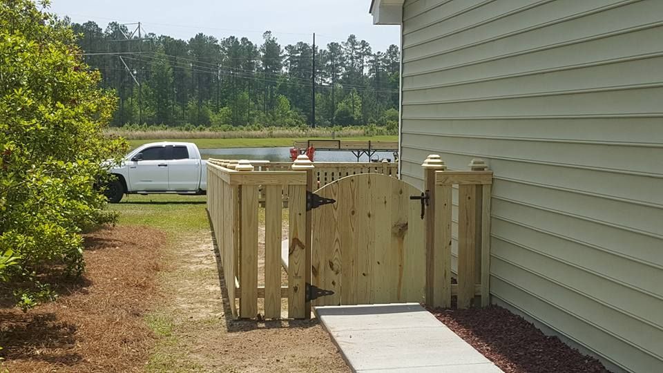 A white truck is parked on the side of a house next to a wooden gate.