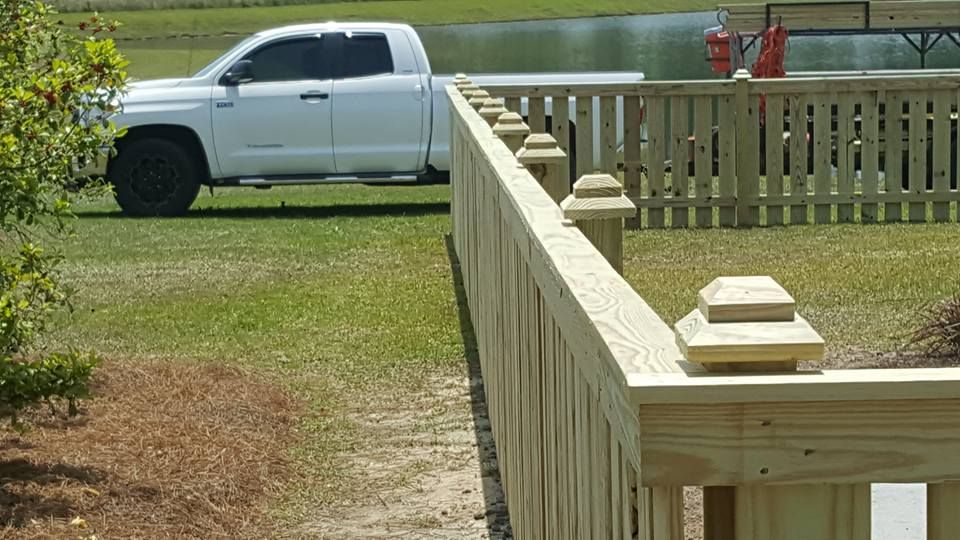 A white truck is parked next to a wooden fence.