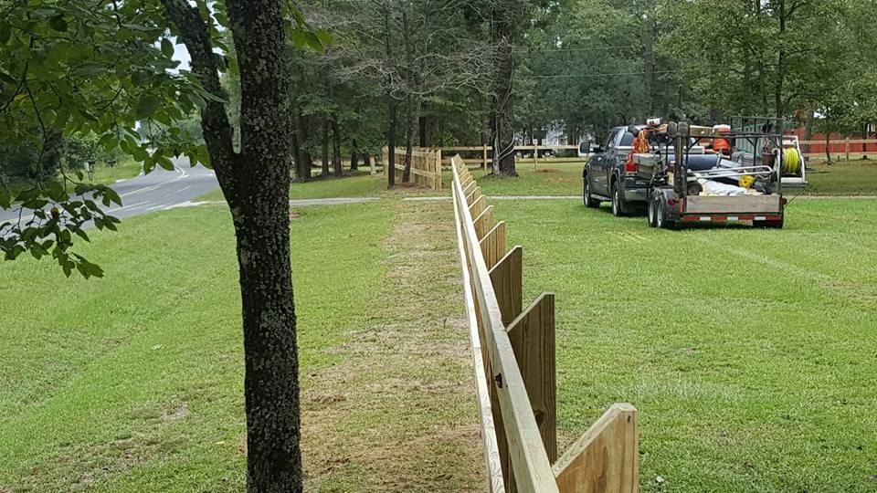 A wooden fence is being built in a grassy field.