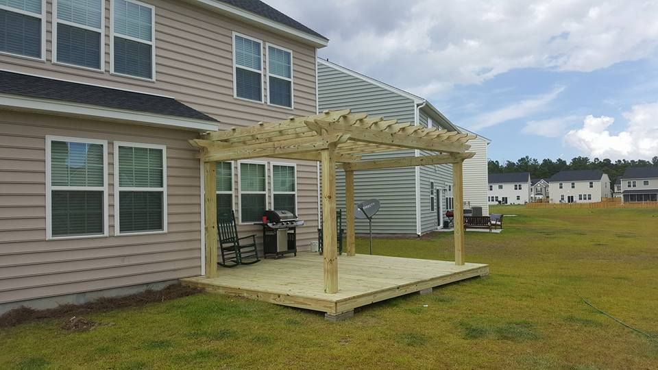A wooden pergola is sitting in the backyard of a house.