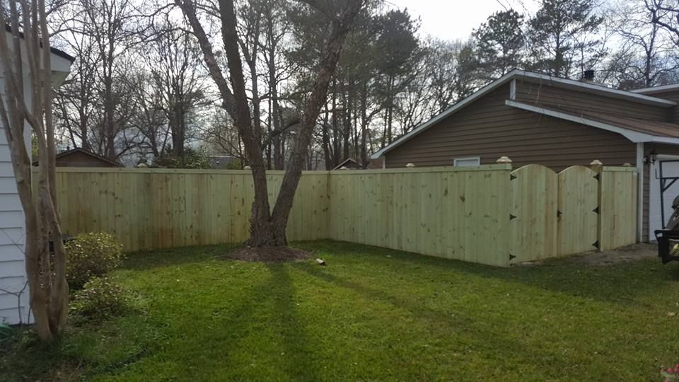 A wooden fence is in the backyard of a house.