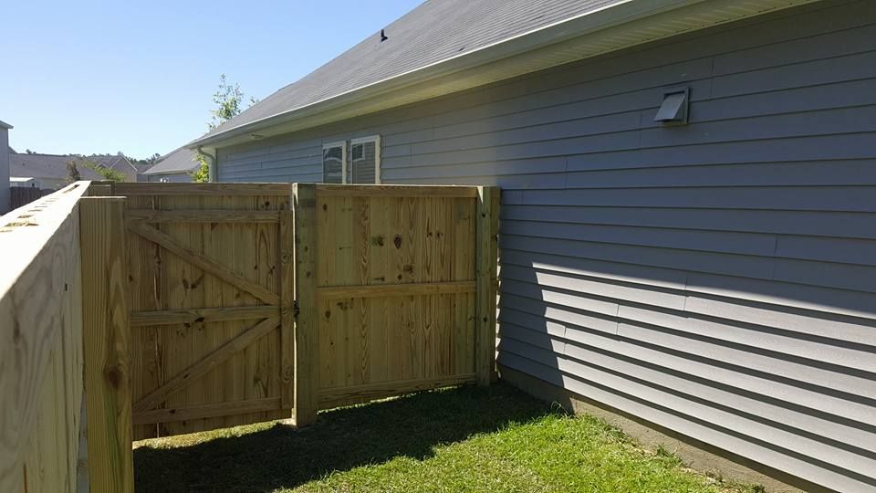 A wooden fence with a gate in the backyard of a house.