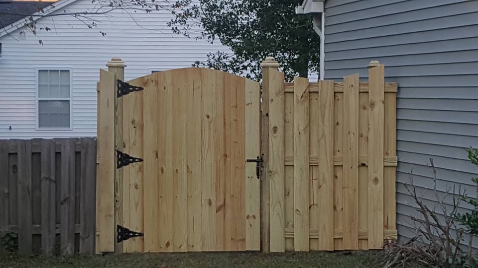 A wooden fence with a gate in front of a house.