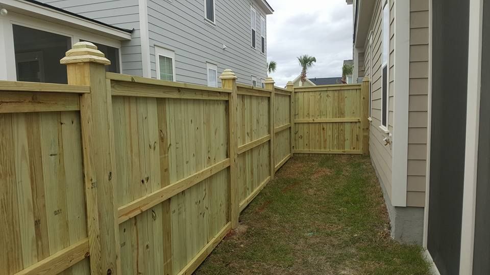 A wooden fence is in the backyard of a house.
