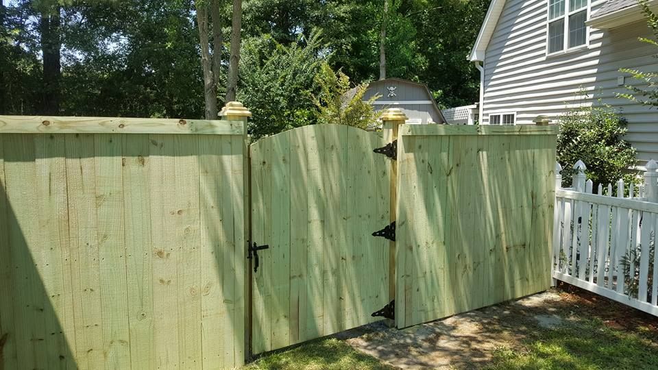 A wooden fence with a gate in the backyard of a house.