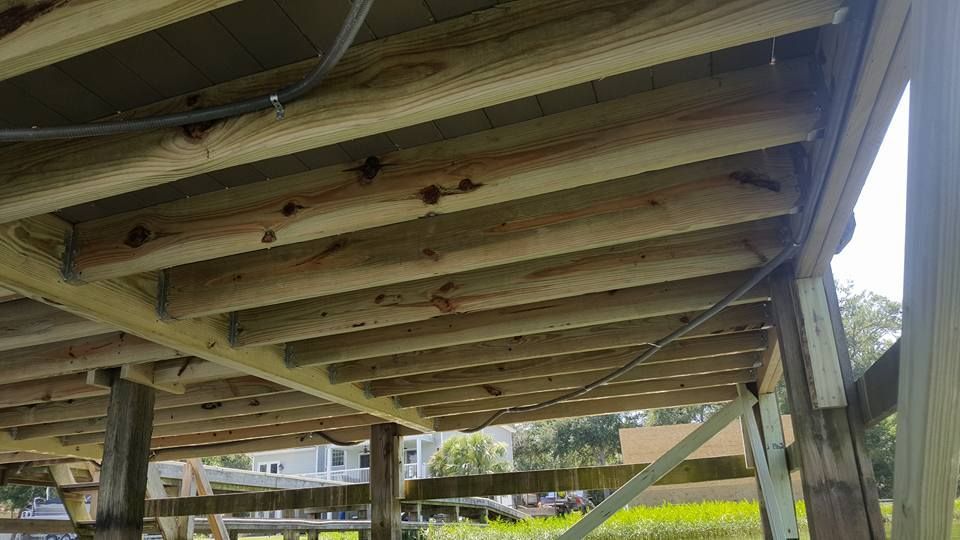 The bottom of a wooden deck with a fence in the background.