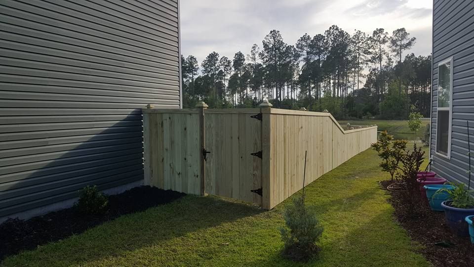 A wooden fence is in the backyard of a house.