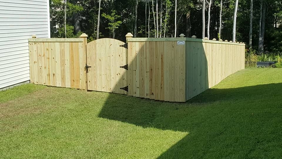 A wooden fence with a gate in the backyard of a house.