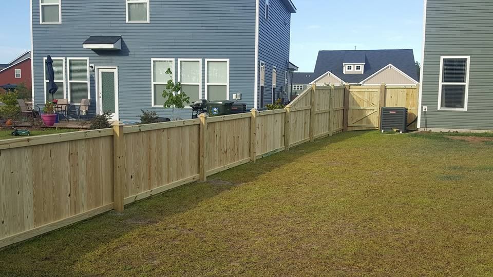 A wooden fence is in the backyard of a house.