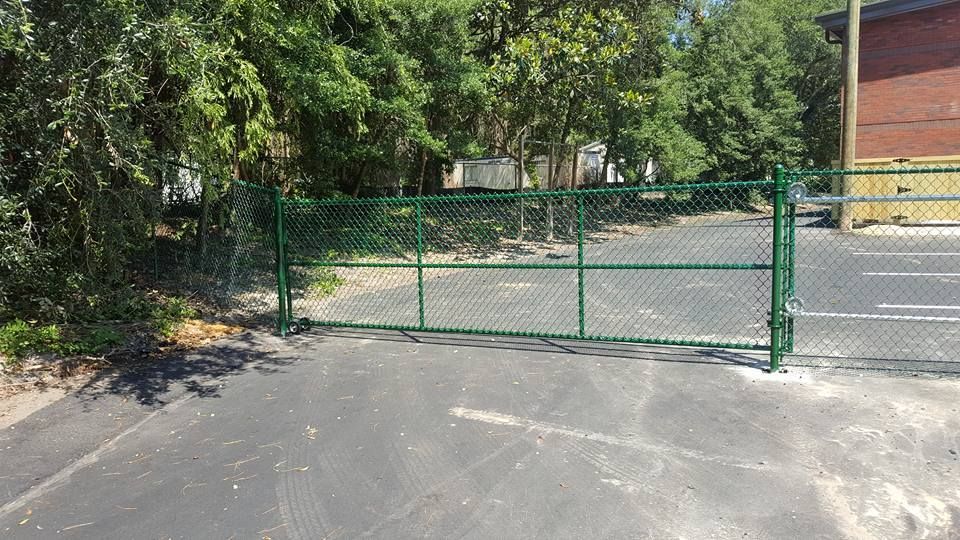 A green chain link fence is surrounding a parking lot.