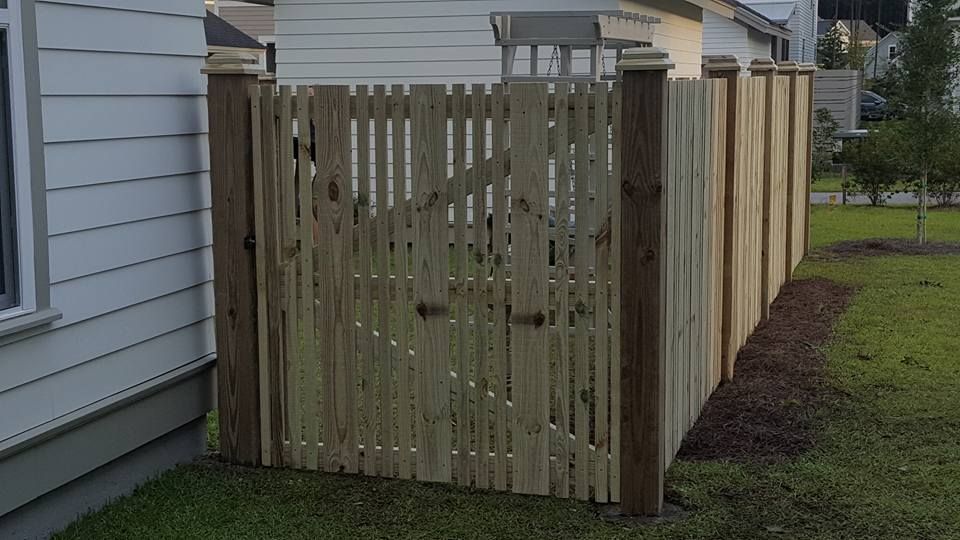 A wooden fence with a gate in the backyard of a house.