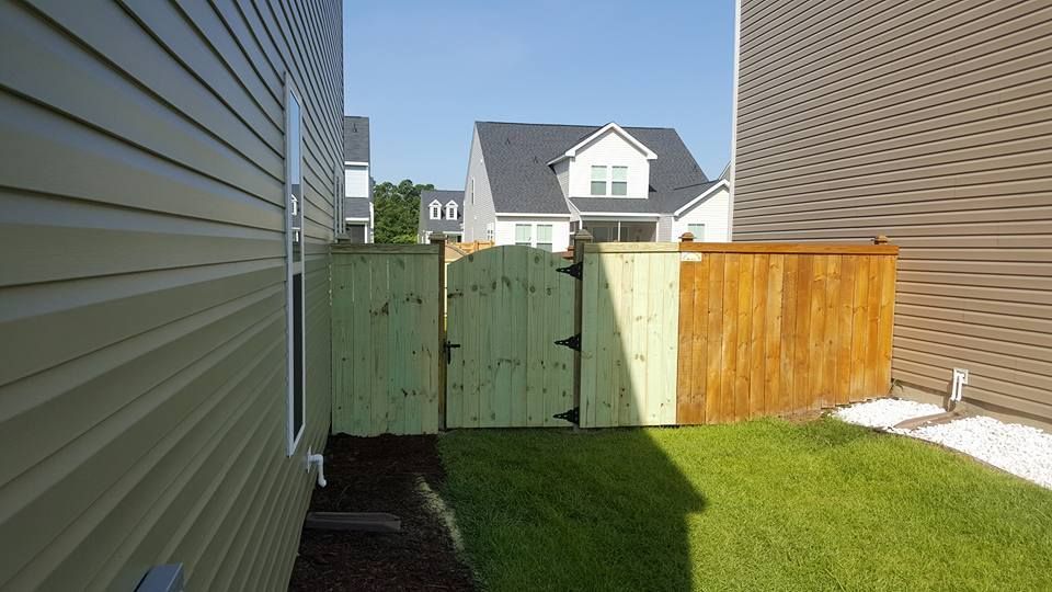 A backyard with a wooden fence and a house in the background