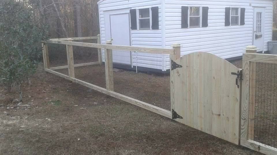 A wooden fence with a gate in front of a white house.