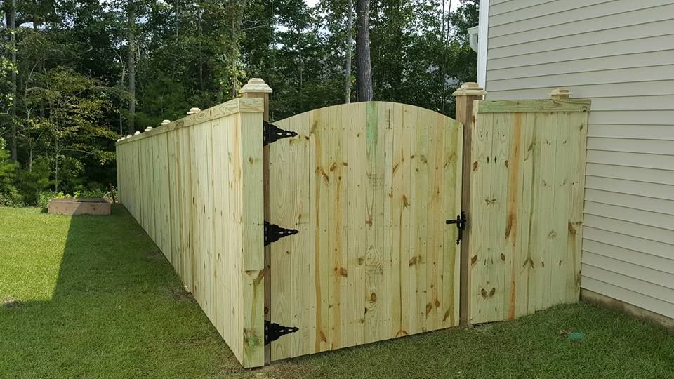 A wooden fence with a gate in the backyard of a house.