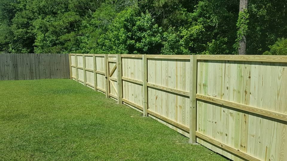 A wooden fence is sitting in the middle of a lush green field.