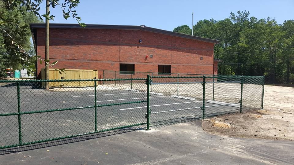 A chain link fence is in front of a brick building