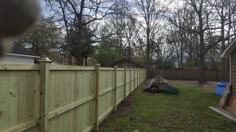 A wooden fence is in the backyard of a house.