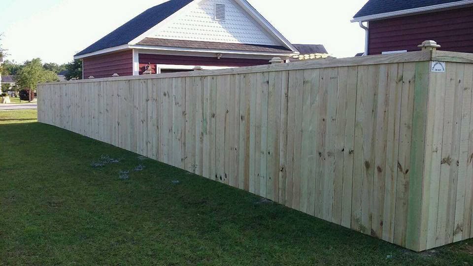 A wooden fence is sitting in the grass in front of a house.